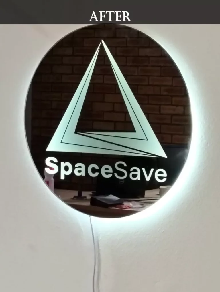 Illuminated circular wall-mounted mirror art featuring the SpaceSave logo with geometric triangle design and backlight effect.